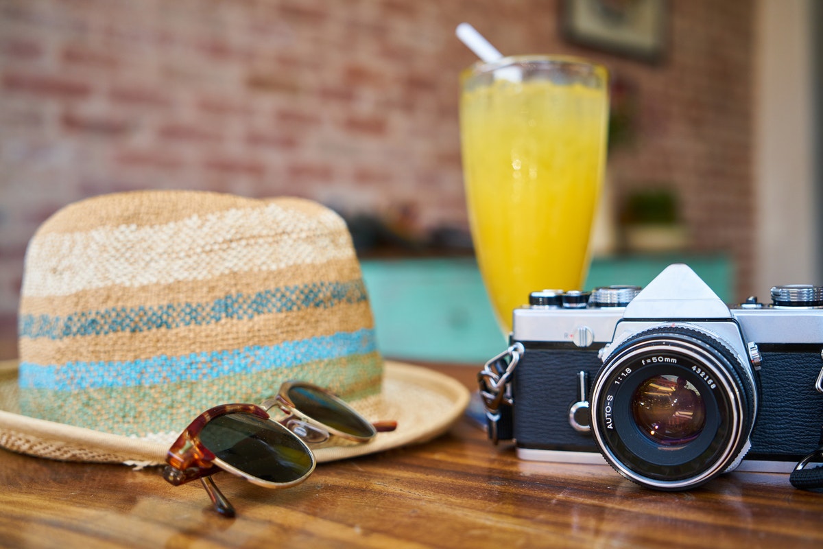 Gray and Black Dslr Camera Beside Sun Hat